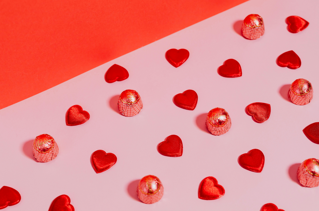 7 of The Best Valentine's Day Gift Ideas of 2025 blog image. Image of a pink and red background with chocolate heats lined up.